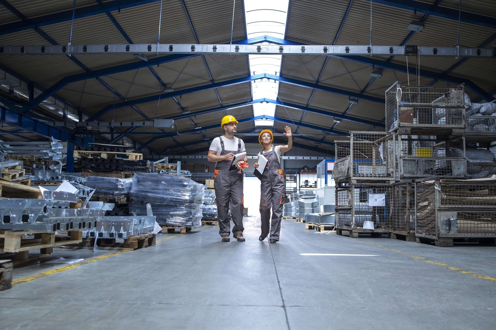 factory workers walking through large production hall min scaled